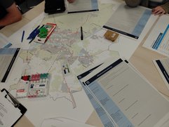 Ein Bild zeigt einen Gruppentisch mit Unterlagen zur Planungswerkstatt am 05.06.2026.
